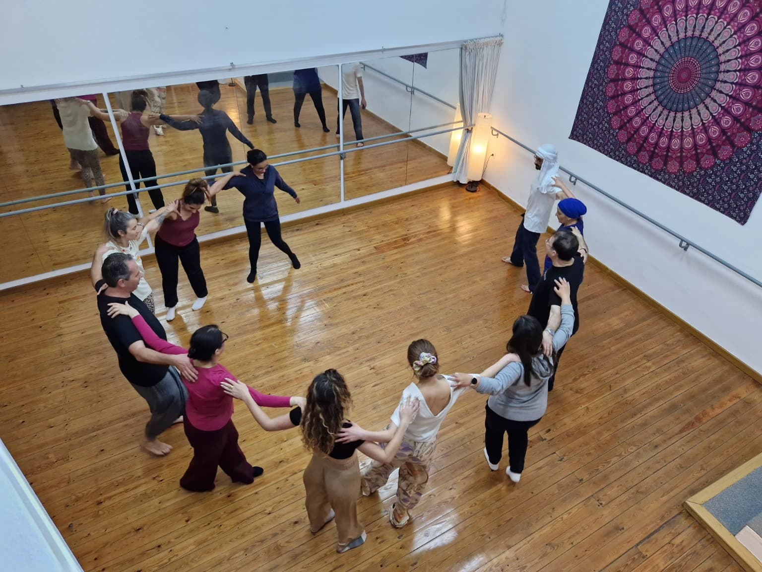 Teilnehmende eines Dabke-Workshops tanzen gemeinsam im Kreis in einem Studio mit Holzboden
